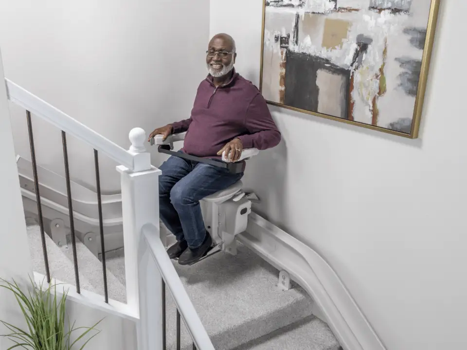 Bruno Elite Curved Indoor Stairlift installed on a staircase with a custom-fit rail, showcasing a plush, adjustable seat, armrests, and footrest. The stairlift highlights its sleek design, smooth curves, and high-quality craftsmanship, blending seamlessly into the home.